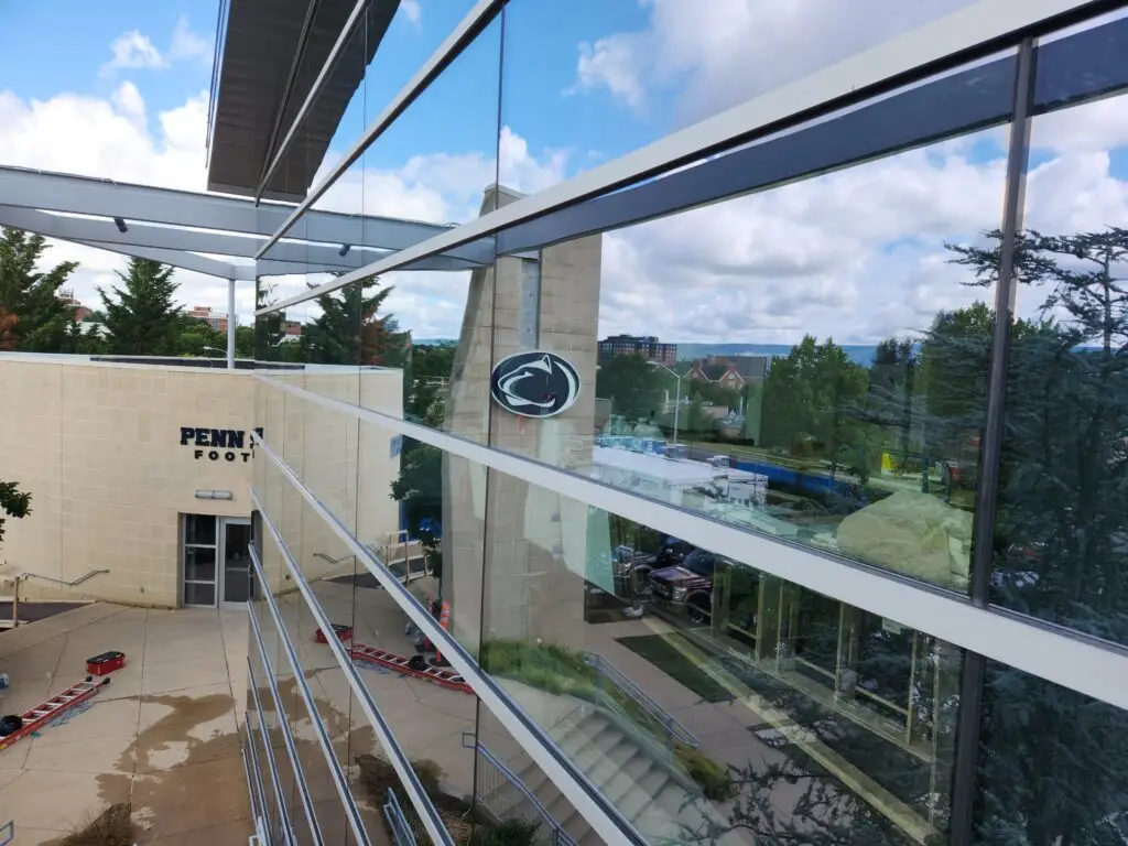 Reflection in high-rise glass windows overlooking the Penn State football building and campus