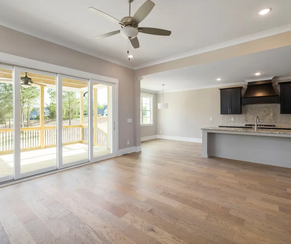 Open concept living room and kitchen with hardwood floors and clean sliding glass doors leading to a porch