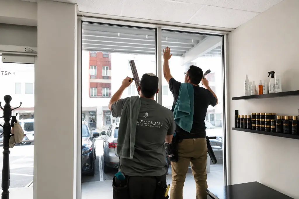 Reflections Window Washing team members squeegeeing large storefront windows inside a retail shop