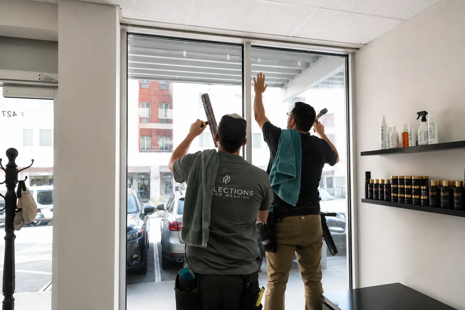 Reflections Window Washing team members squeegeeing large storefront windows inside a retail shop