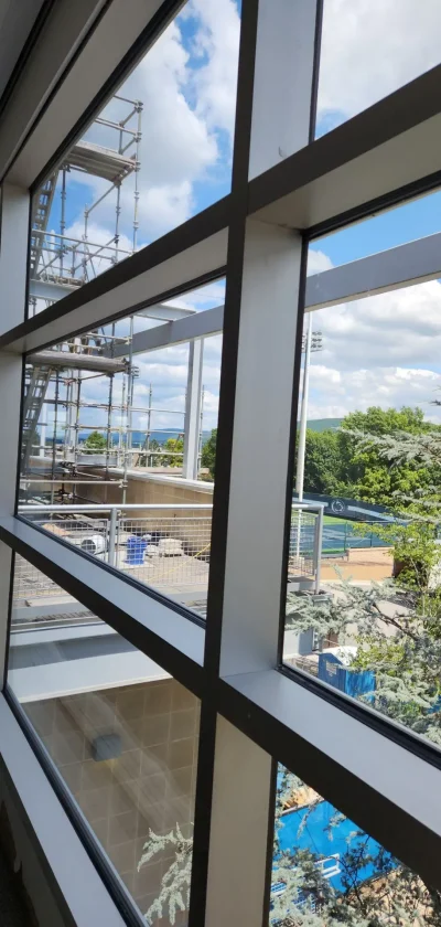 Clean high-rise interior window overlooking trees and a rooftop courtyard with construction scaffolding in view