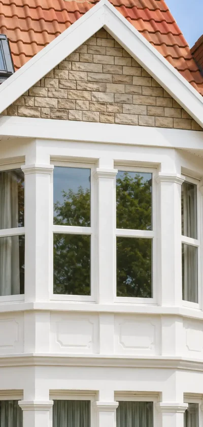 Second-story white bay window with spotless glass panes on a residential stone house